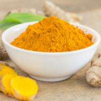 Golden turmeric powder, white bowl, fresh root slices SoilSaga Naturals fine milling